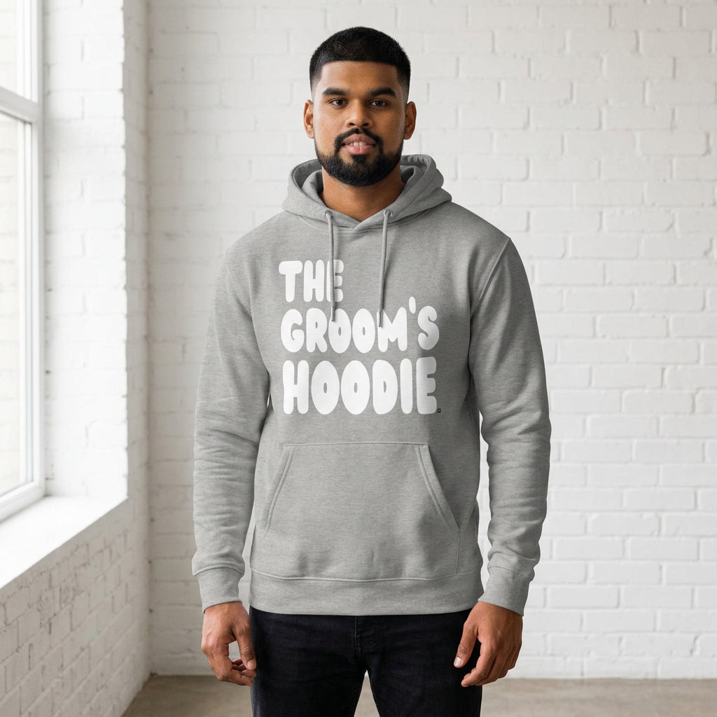 Man wearing the Groom's Hoodie Premium Unisex Hoodie From the APWT Wedding Shop in Grey