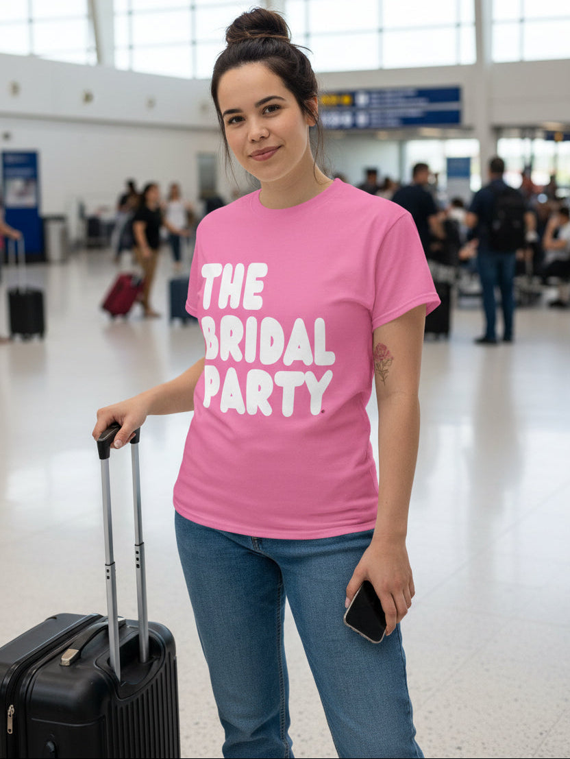 Woman standing in the airport wearing the APWT Gift Shop's the Bridal Party Unisex T-Shirt in Pink from the APWT Wedding Shop Collection