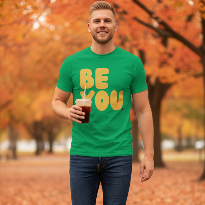 Man standing in the park on an autumn day wearing the APWT Gift Shop's Be You in Green and Yellow Unisex T-Shirt from the Be You Collection