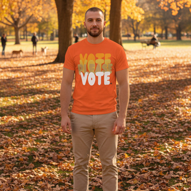 Man standing in the park on an autumn day wearing the APWT Gift Shop's Please Vote in Safety Cone Orange Unisex T-Shirt from the APWT Vote Shop