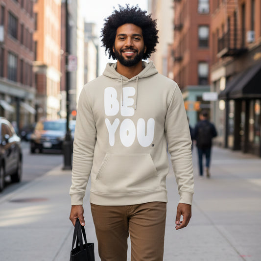 Man walking down a city street wearing the APWT Gift Shop's Be You in Beige and White Premium Unisex Hoodie from the Be You Collection and the Premium Basics Collection