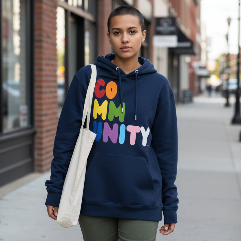 Woman walking down a city sidewalk wearing the APWT Gift Shop's Rainbow Community Premium Unisex Hoodie from the Community Collection and the Pride in the APWT Gift Shop Collection