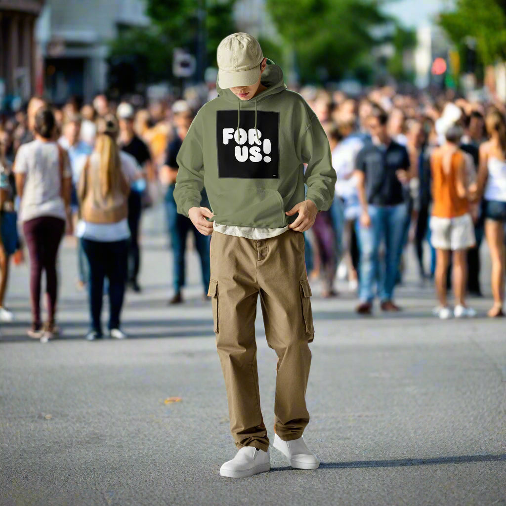 Man wearing the For Us in Black and White Unisex Hoodie in Military/Army Green standing in a crowd of people on a city street - The APWT Gift Shop