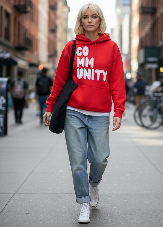 Woman walking down a city street wearing the APWT Gift Shop's A Community in Balloon Red Unisex Hoodie from the Community Collection
