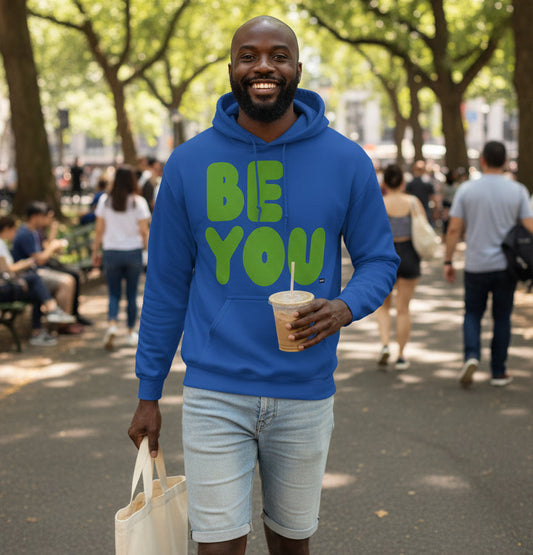 man walking through a city park wearing the APWT Gift Shops Be You in Blue and Green Unisex Hoodie from the Be You Collection