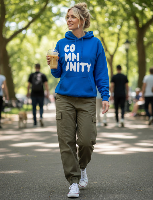 Woman walking through a park wearing The APWT Gift Shop's A Community in Ocean Blue Unisex Hoodie from the Community Collection