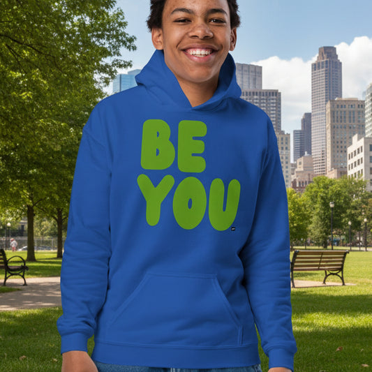 Boy in park wearing Be You Kids in Green Unisex Hoodie in Royal Blue from the APWT Gift Shop - Kids Affirmation Sweatshirts