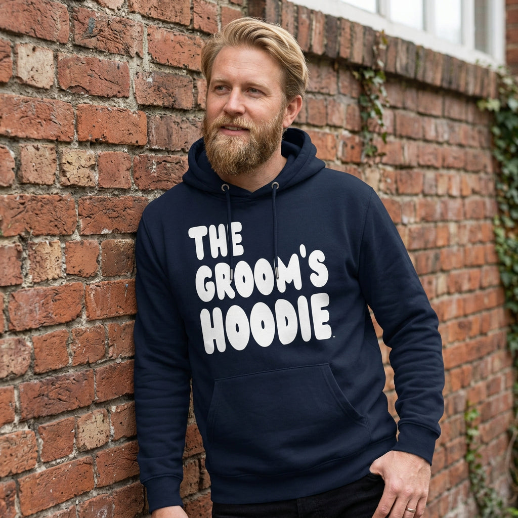 Man wearing the Groom's Hoodie Premium Unisex Hoodie From the APWT Wedding Shop in Navy Blue