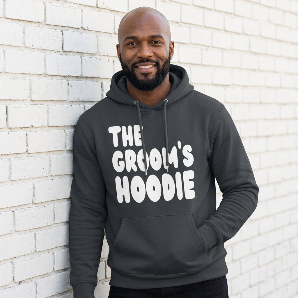 Man wearing the Groom's Hoodie Premium Unisex Hoodie From the APWT Wedding Shop in Dark Grey