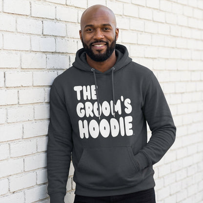 Man wearing the Groom's Hoodie Premium Unisex Hoodie From the APWT Wedding Shop in Dark Grey