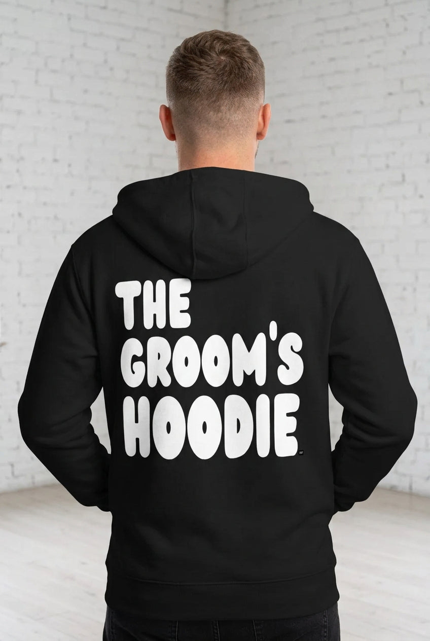 Man wearing the Groom's Hoodie Premium Unisex Zip-Up Hoodie From the APWT Wedding Shop in Black - Back View