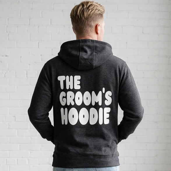 Man wearing the Groom's Hoodie Premium Unisex Zip-Up Hoodie From the APWT Wedding Shop in  Dark Grey - Back View