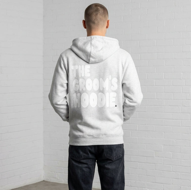 Man wearing the Groom's Hoodie Premium Unisex Zip-Up Hoodie From the APWT Wedding Shop in Grey - Back View