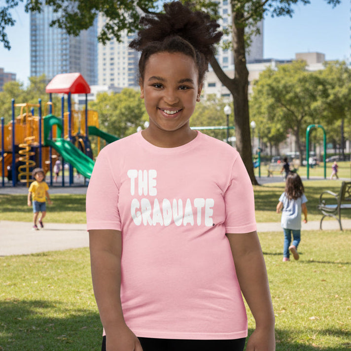Girl wearing The Graduate Kid's Unisex T-Shirt in Pink from the APWT Gift Shop