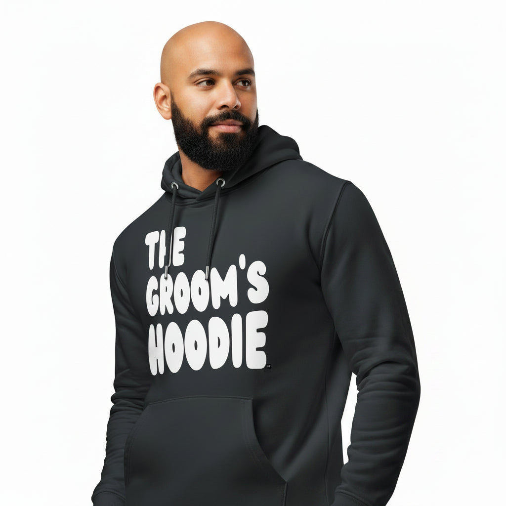 Man wearing the APWT Gift Shop's The Groom's Hoodie Premium Unisex Hoodie from the APWT Wedding Shop in Charcoal Grey