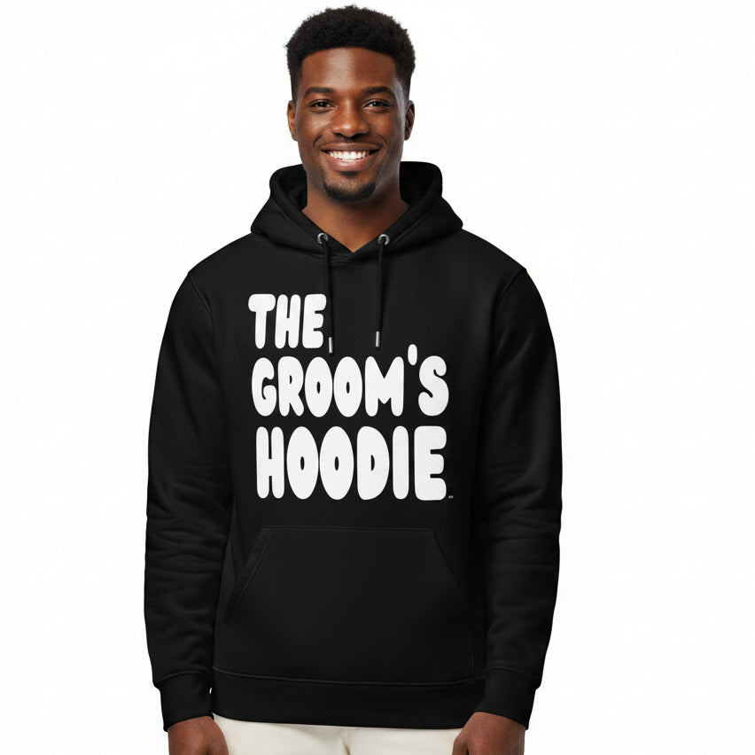 Man wearing the APWT Gift Shop's The Groom's Hoodie Premium Unisex Hoodie from the APWT Wedding Shop in Black