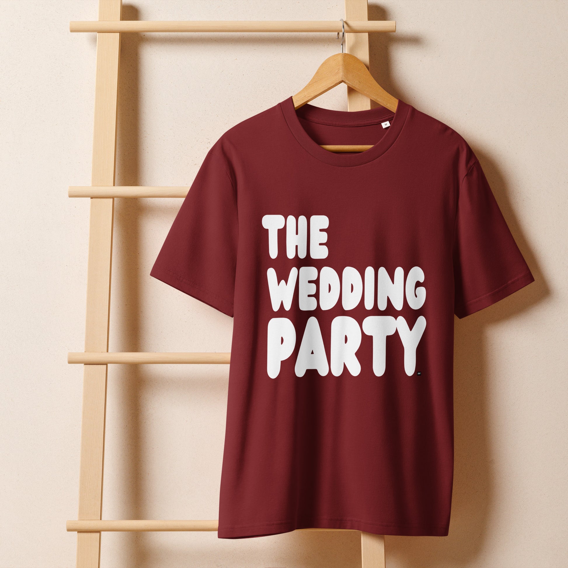 The Wedding Party Premium Unisex T-Shirt in Burgundy from the APWT Gift Shop on a hanger