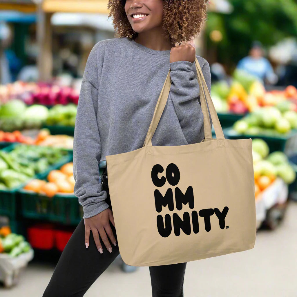 Woman holding the Community in Black Jumbo Tote Bag from the APWT Gift Shop