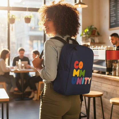 Woman standing in a coffee shop wearing the APWT Gift Shop's Rainbow Community Backpack from the Pride in the APWt Gift Shop Collection