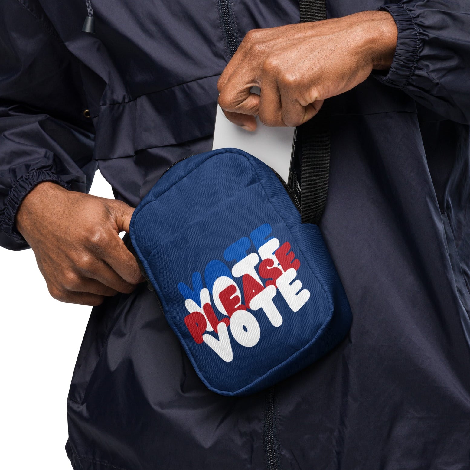 close up of hand putting cellphone in The APWT Gift Shop's Please Vote Small Crossbody Bag from the APWT Vote Shop