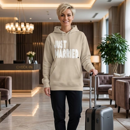 Woman standing in a hotel lobby wearing the APWT Gift Shop's Just Married Premium Unisex Hoodie from the APWT Wedding Shop and the Premium Basics Collection in beige