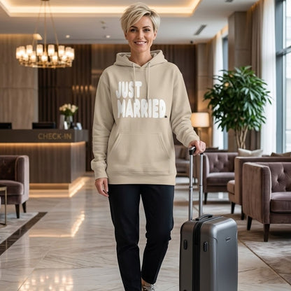 Woman standing in a hotel lobby wearing the APWT Gift Shop's Just Married Premium Unisex Hoodie from the APWT Wedding Shop and the Premium Basics Collection in beige