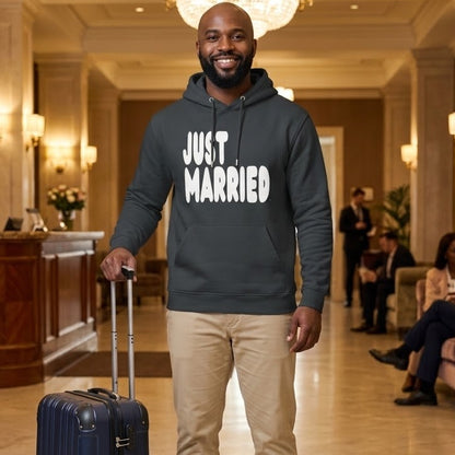 Man standing in a hotel lobby wearing the APWT Gift Shop's Just Married Premium Unisex Hoodie from the APWT Wedding Shop and the Premium Basics Collection in dark grey