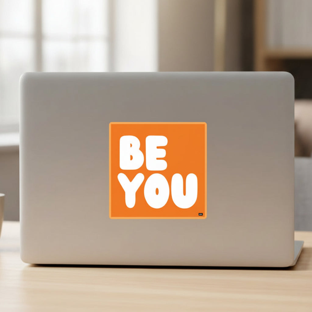 The APWT Gift Shop's Be You in Orange Vinyl Sticker stuck to the back of a laptop