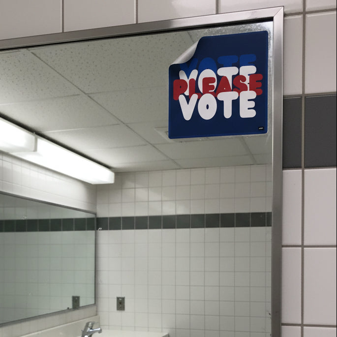 The APWT Gift Shop's Please Vote Vinyl Sticker from the APWT Vote Shop stuck to the mirror in a public bathroom