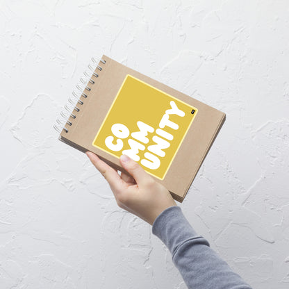 A Community in Yellow Vinyl Sticker on a notebook - The APWT Gift Shop