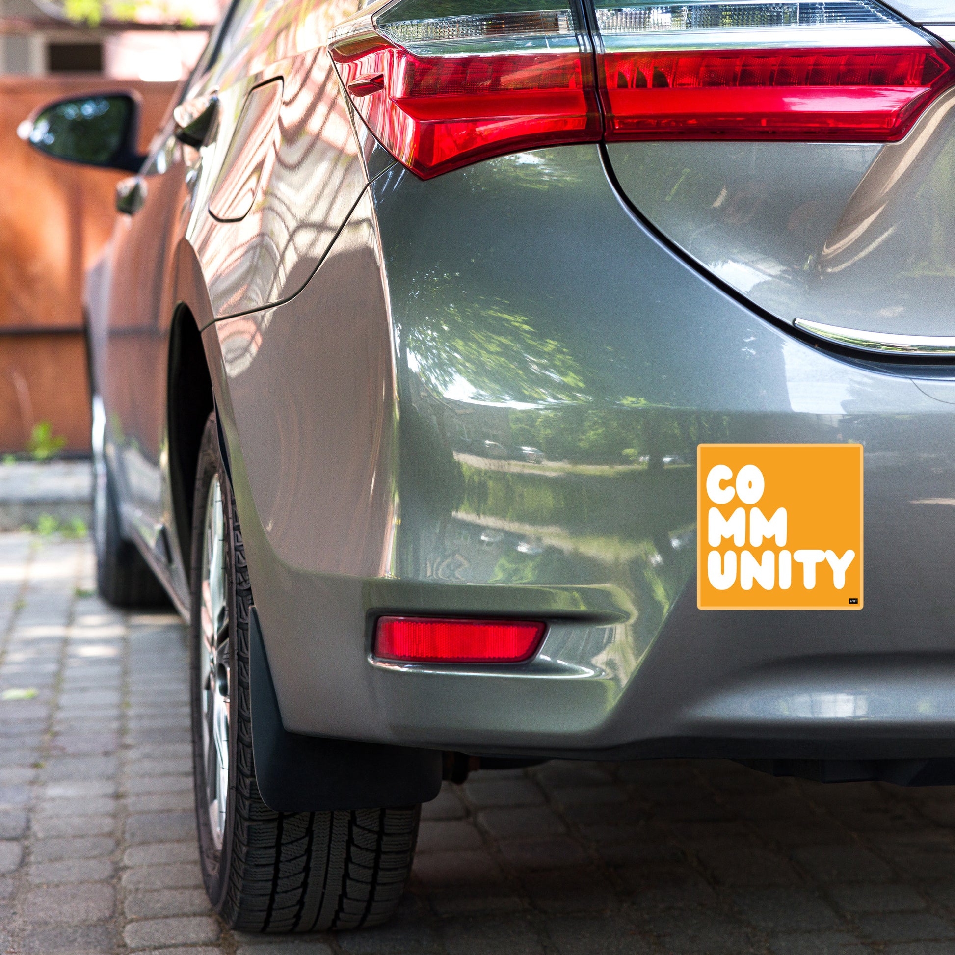 A Community in Orange Vinyl Sticker on a car bumper - The APWT Gift Shop