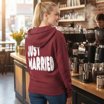 Woman standing in a coffee shop wearing the APWT Gift Shop's Just Married Premium Unisex Zip-Up Hoodie in Burgundy from the APWT Wedding Shop