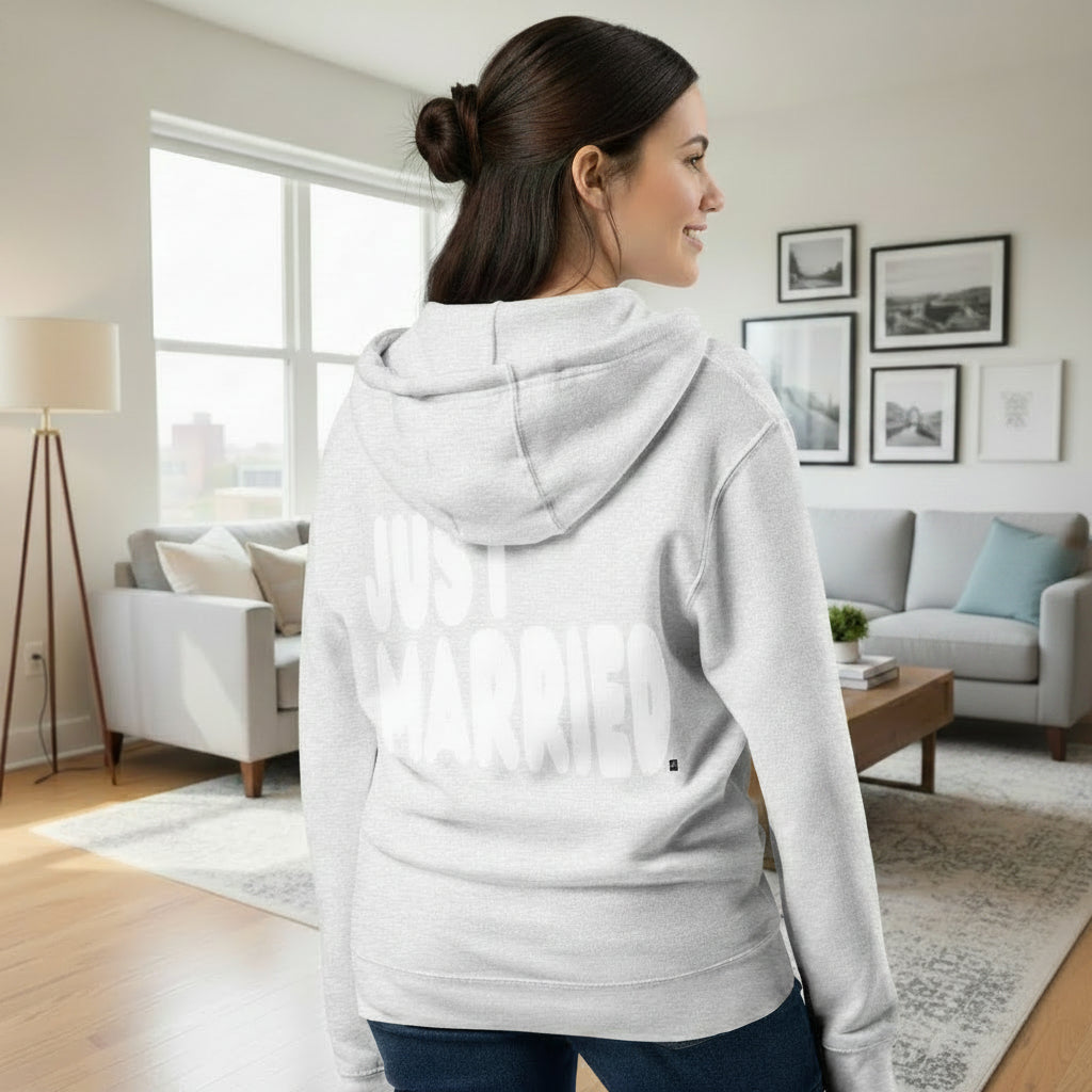 Woman standing in a living room wearing the APWT Gift Shop's Just Married Premium Unisex Zip-Up Hoodie in Grey from the APWT Wedding Shop