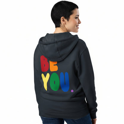 Woman wearing the APWT Gift Shop's Rainbow Be You Premium Unisex Zip-Up Hoodie from the Pride in the APWT Gift Shop Collection in Navy Blue