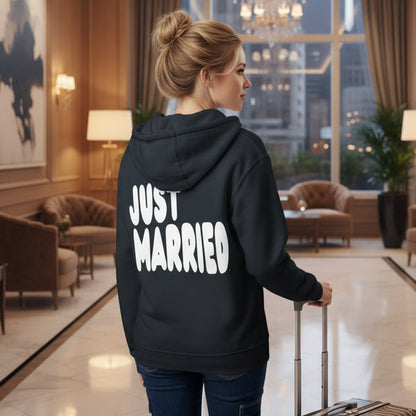 Woman standing in a hotel lobby wearing the APWT Gift Shop's Just Married Premium Unisex Zip-Up Hoodie in Navy Blue from the APWT Wedding Shop