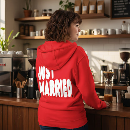 Woman standing in a coffee shop wearing the APWT Gift Shop's Just Married Premium Unisex Zip-Up Hoodie in Red from the APWT Wedding Shop