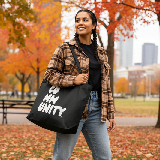 Woman walking in a city park carrying the APWT Gift Shop's Community in Black and White Jumbo Tote Bag from the Community Collection