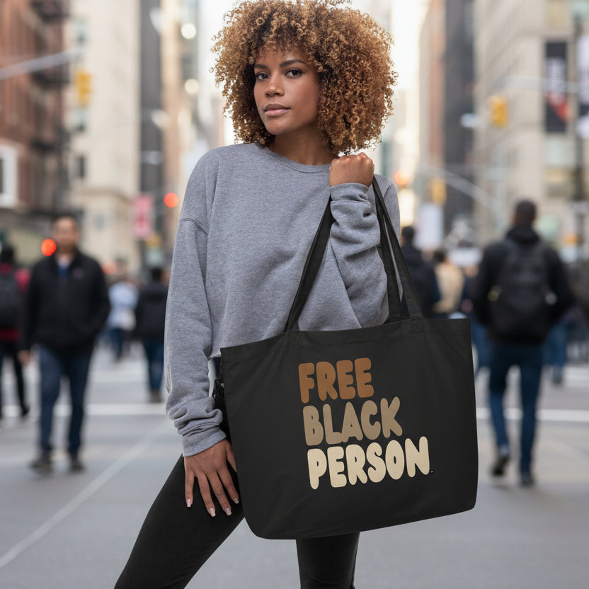 Person holding a black tote bag with 'FREE BLACK PERSON' text.