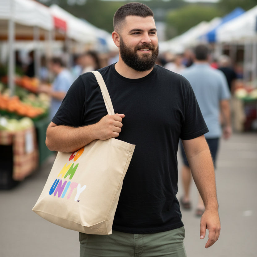 Man carrying the APWT Gift Shop's Rainbow Community Jumbo Tote Bag from the Pride in the APWT Gift Shop Collection