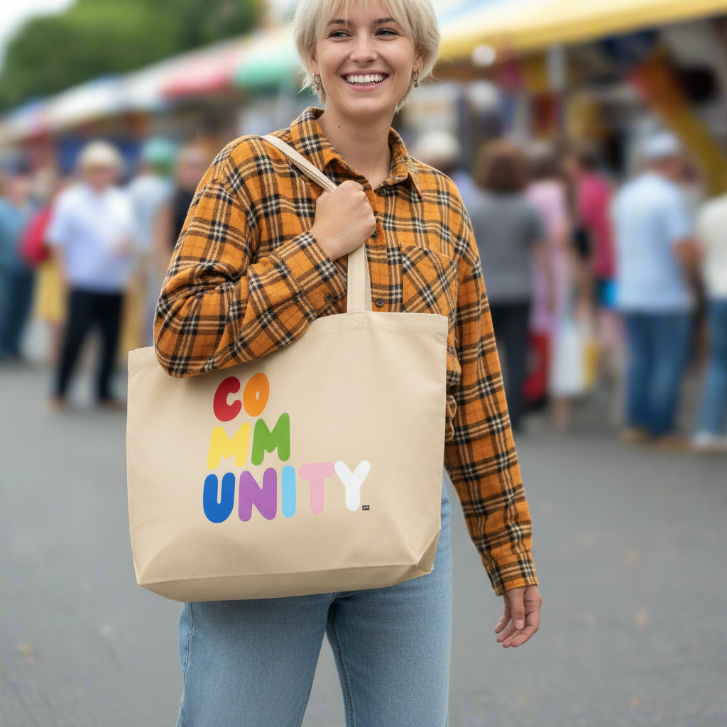 Woman carrying the APWT Gift Shop's Rainbow Community Jumbo Tote Bag from the Pride in the APWT Gift Shop Collection