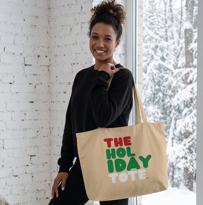 Woman holding the APWT Gift Shop's Holiday Tote Jumbo Tote Bag from the APWT Holiday Shop
