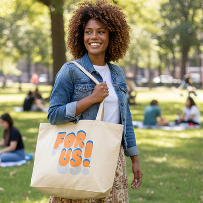 Woman in a city park wearing the APWT Gift Shop's For Us in Blue and Orange Jumbo Tote Bag in Natural