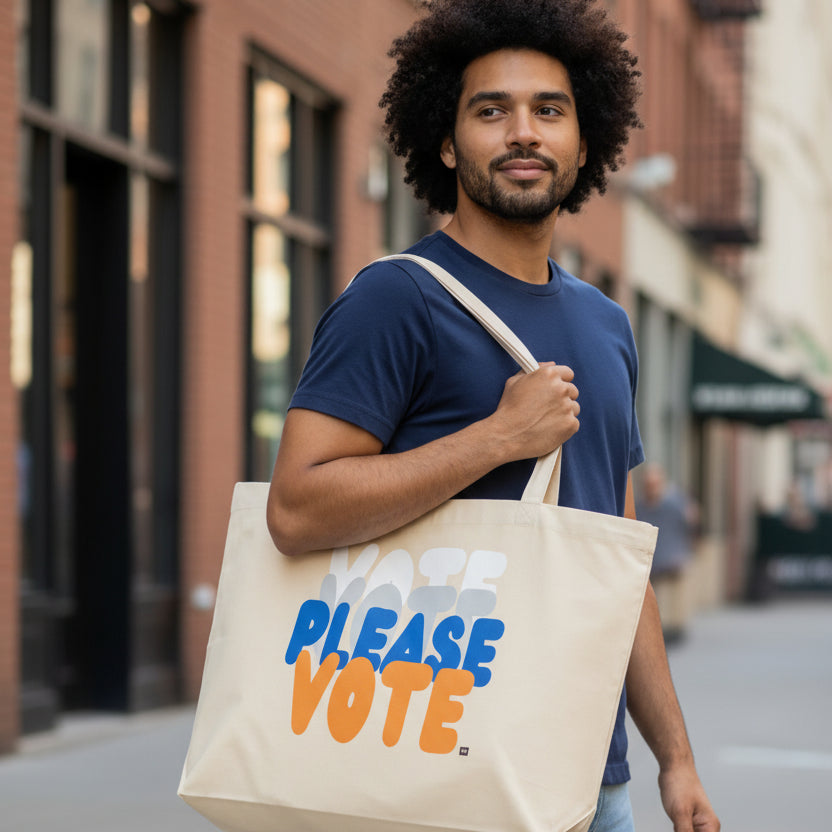 Man wearing the the APWT Gift Shop's Please Vote in Blue and Orange Jumbo Tote Bag from the APWT Vote Shop in natural