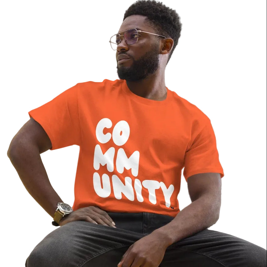 man wearing A Community in Orange Citrus Unisex T-Shirt from the APWT Gift Shop sitting