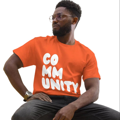 man wearing A Community in Orange Citrus Unisex T-Shirt from the APWT Gift Shop sitting