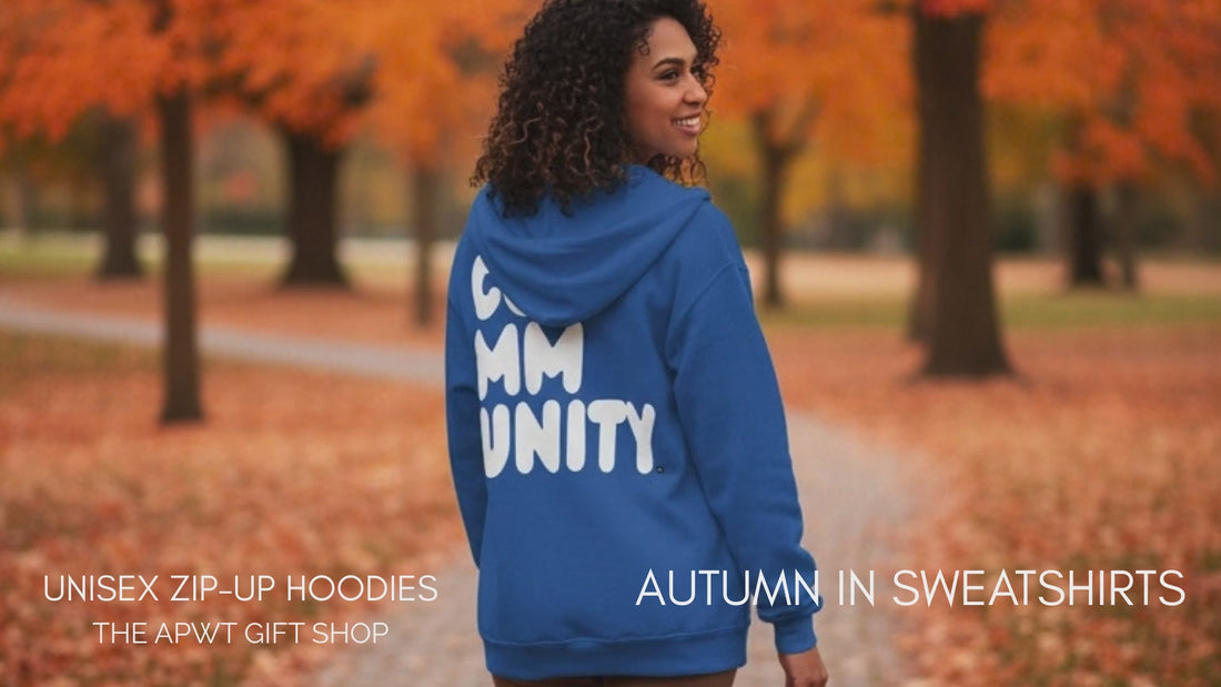 Woman and man walking through the park on an autumn day wearing the APWT Gift Shop's A Community in Ocean Blue Unisex Zip-Up Hoodie from the Community Collection