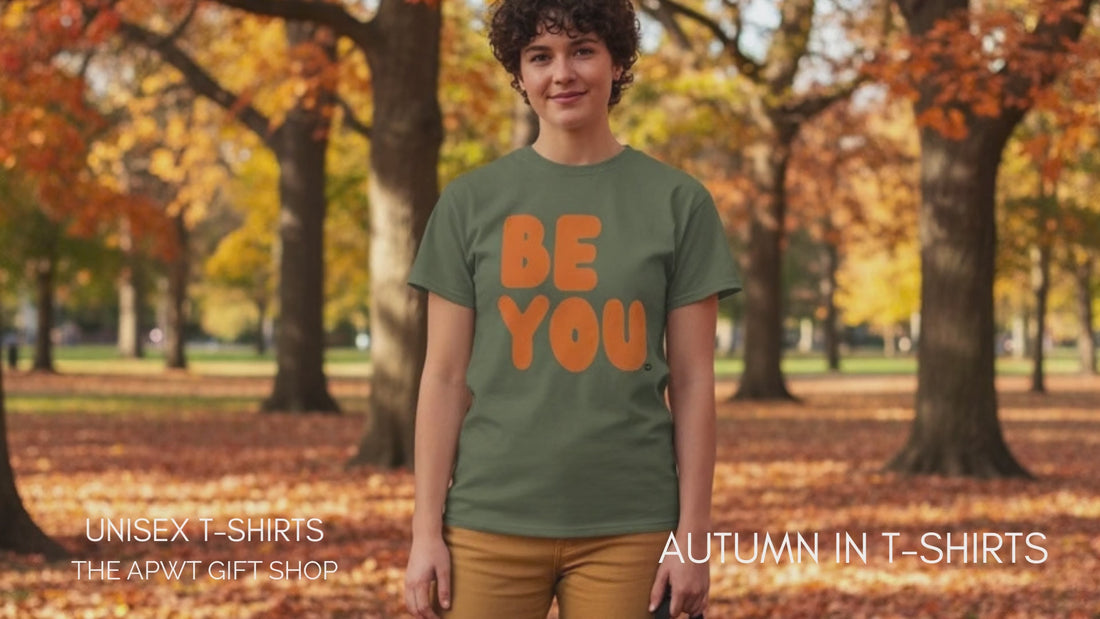 Woman standing in the park on an autumn day wearing the APWT Gift Shop's Be You in Olive Green and Orange Unisex T-Shirt from the Be You Collection