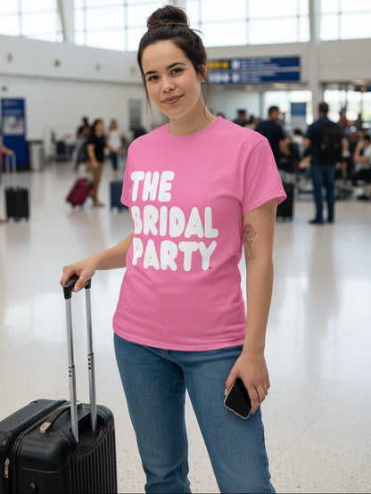 Woman standing in the airport wearing the APWT Gift Shop's the Bridal Party Unisex T-Shirt in Pink from the APWT Wedding Shop Collection