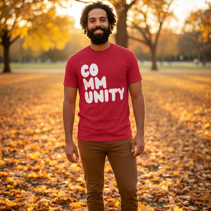 Man standing in the park on an autumn day wearing the APWT Gift Shop's A Community in Apple Red Unisex T-Shirt from the Community Collection