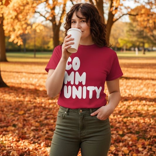 Woman standing in the park on an autumn day wearing the APWT Gift Shop's A Community in Apple Red Unisex T-Shirt from the Community Collection